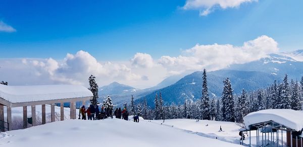 Panoramic view of people on snowcapped mountains against sky