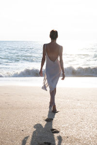 Rear view of woman standing at beach