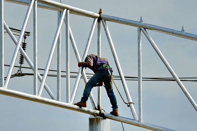 Low angle view of child on bridge against sky