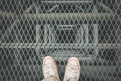 Low section of man standing on chainlink fence
