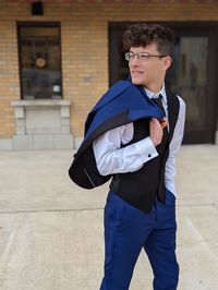 Portrait of young man waking in front of building