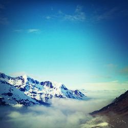 Scenic view of snow covered mountains against blue sky