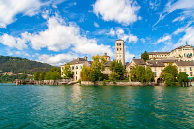 Isola san giulio inside orta's lake, piemonte, italy, from water surface with blue sky.