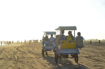 Rear view of people walking on field against clear sky