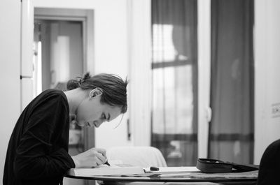 Side view of young woman studying at table