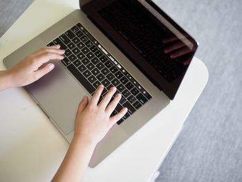 Cropped hands of woman using laptop