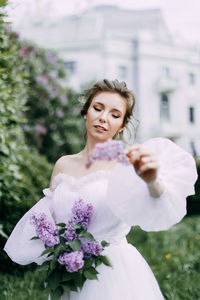 Beautiful bride in a wedding dress walks in a blooming apple-tree park in spring