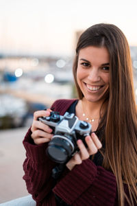 Portrait of a smiling young woman holding camera