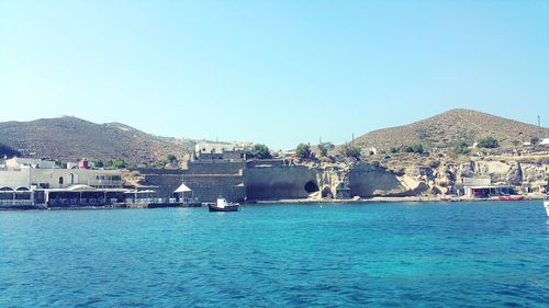 Scenic view of sea and buildings against clear sky
