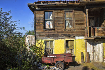 Abandoned house by building against sky