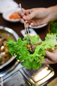 Close-up of hand holding fresh food with chopsticks at table