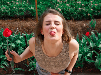 High angle view of woman sticking out tongue while standing against plants