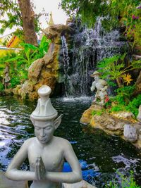 Statue by fountain against trees