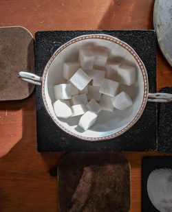 High angle view of sugar cubes in cup on sunlit table