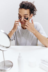 Portrait of young woman using mobile phone against white background