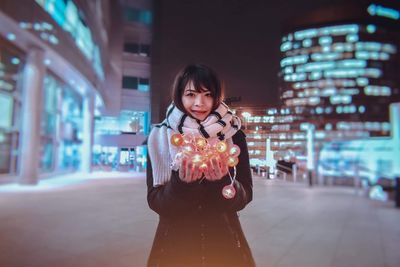 Portrait of woman standing on street at night