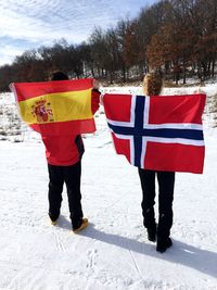 Full length of young couple standing on snow covered landscape