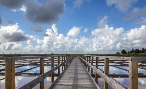 Footbridge over sea against sky