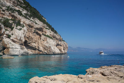 Scenic view of sea and rocks against clear blue sky