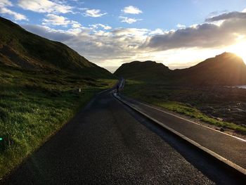 Road amidst mountains against sky during sunset