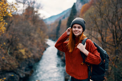 Smiling young woman standing against trees during winter