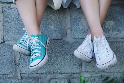 Low section of people wearing canvas shoes on footpath