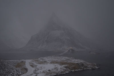 Scenic view of mountains against sky in snowfall