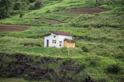 House on field against trees and houses