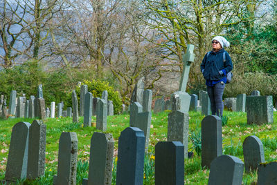 Woman with hands in pockets standing in grave yard