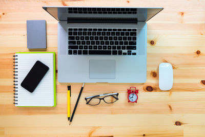 Directly above shot of laptop and accessories on wooden table