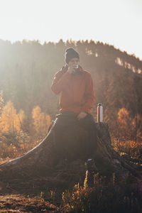 Active hiker sits on fire drinking hot tea to warm up at sunrise. beskydy mountains, czech republic