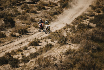 People riding motorcycle on dirt road