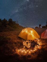 Illuminated tent on field against sky at night