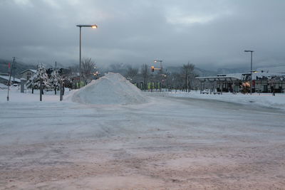 Snow covered street by buildings against sky