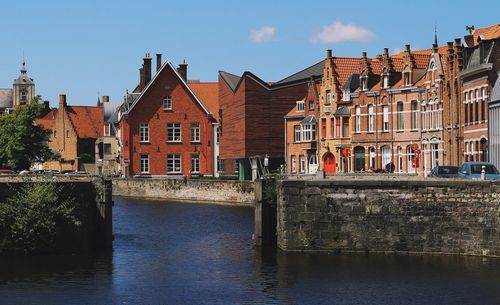 Buildings by river against sky in city