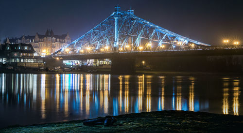 Illuminated bridge over river at night