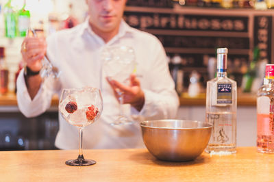 Midsection of bartender preparing drink at counter