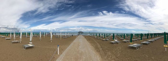 Panoramic view of parasols and chairs at beach against sky