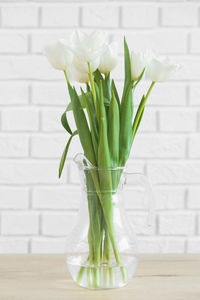 Close-up of white flower vase on table against wall