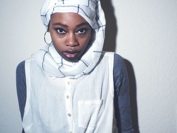 Portrait of young woman standing against white background