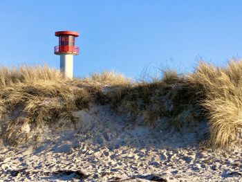 Lighthouse on field against clear blue sky