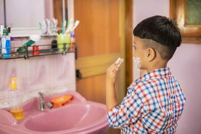 Boy holding umbrella in bathroom at home