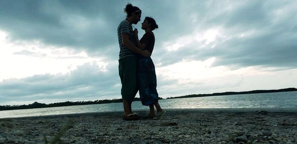 Couple standing at beach against sky