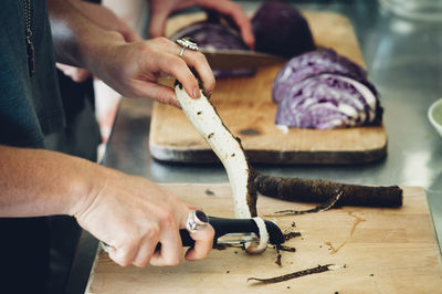 Cropped image of women cutting vegetables on board