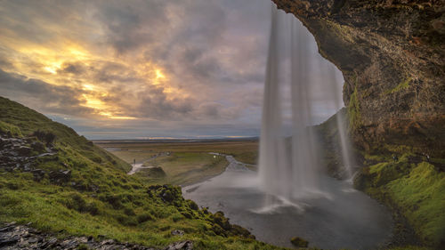 Scenic view of waterfall against sky during sunset