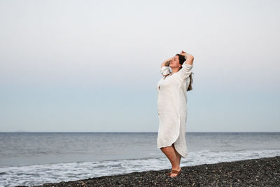 Rear view of woman standing at beach against clear sky