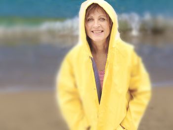 Portrait of senior woman wearing yellow raincoat at beach