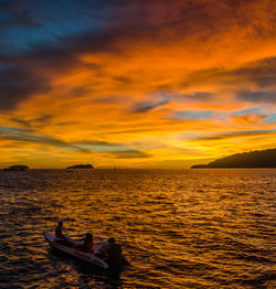 Silhouette man in sea against sky during sunset