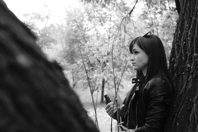 Side view of young woman sitting on tree trunk