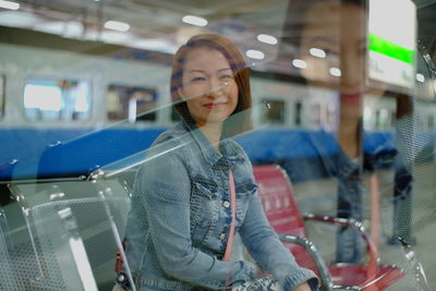 Double exposure image of young woman sitting on bench at railroad station